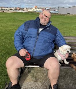 A man sitting on a park bench with his dog.