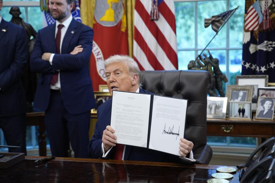 President Donald Trump speaks as he holds up executive orders signed in the Oval Office.