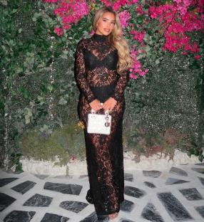 Ella Barnes in a sheer black lace dress and white handbag.