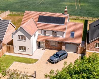 Aerial view of a house with solar panels on the roof and a car in the driveway.