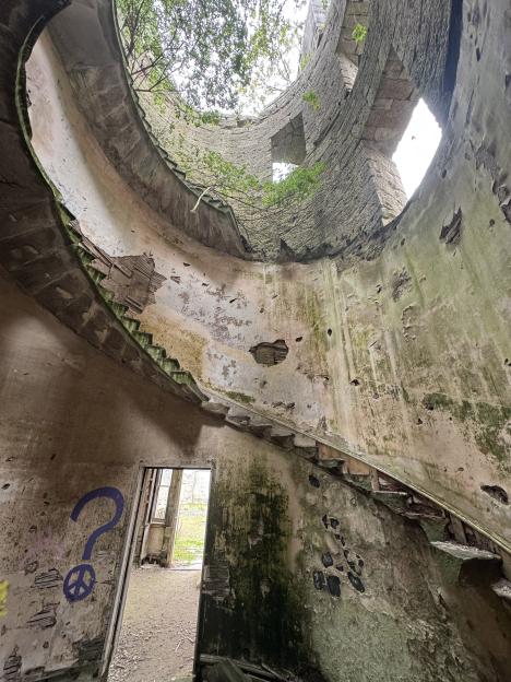 Ruined interior of Dalquharran Castle showing a decaying spiral staircase.