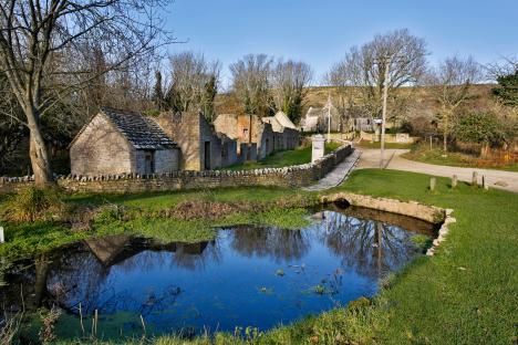 Ruins of a village reflected in a pond.