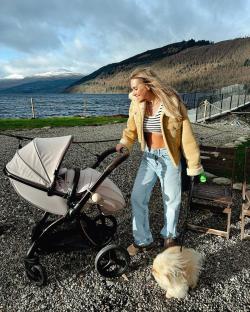 Woman with baby stroller and dog by a lake.