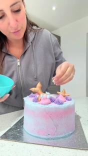Person decorating a mermaid-themed cake.