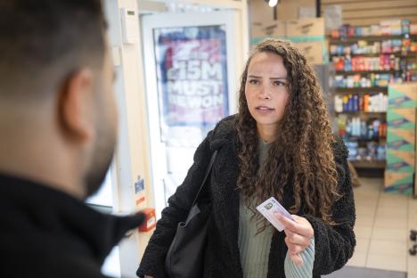 Woman showing ID to clerk.