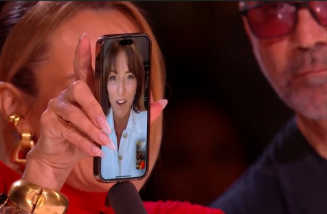 A woman holding a phone showing a video call on Britain's Got Talent.