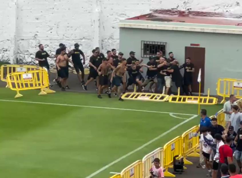 Police officers intervening in a fight between rival fans at a soccer game.