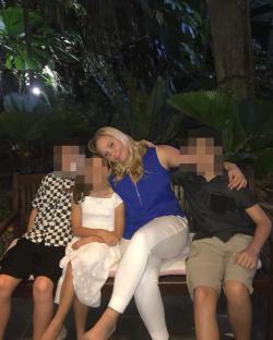 Woman sitting on a bench with three children.