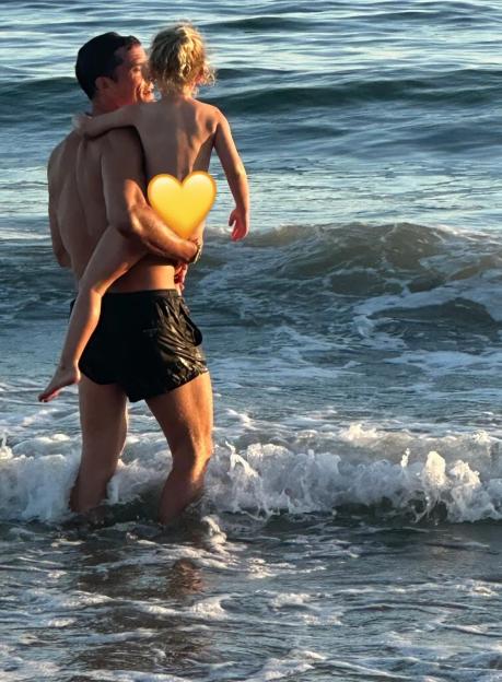 Orlando Bloom carrying his young daughter in the ocean.