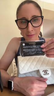 Woman showing a Chanel bag and authenticity card.