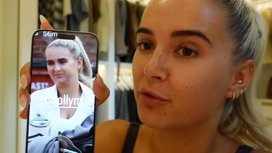 Woman holding phone displaying a photo of herself, expressing concern about her appearance in the photo.