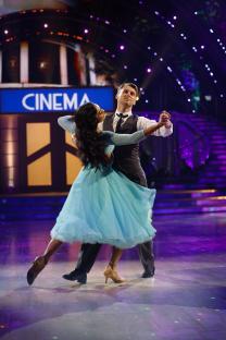 Two dancers in ballroom attire performing on a stage.