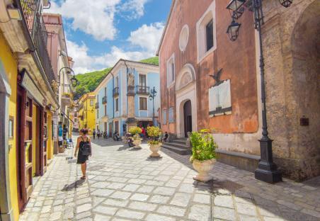 Woman walking down a cobblestone street in a colorful Italian village.