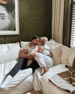 Molly Mae and Tommy Fury kissing on a couch with their baby.