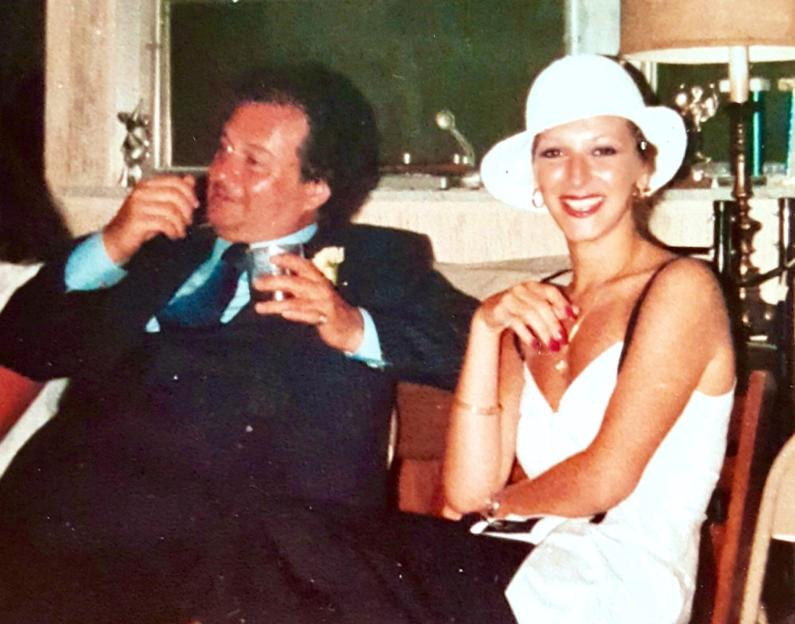 a man in a suit and tie sits next to a woman in a white hat