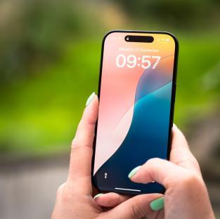Close-up of a woman's hands holding and using a new iPhone 16 Pro.
