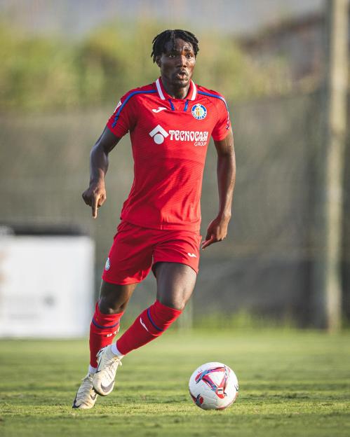 Soccer player Christantus Uche in red uniform dribbling the ball.