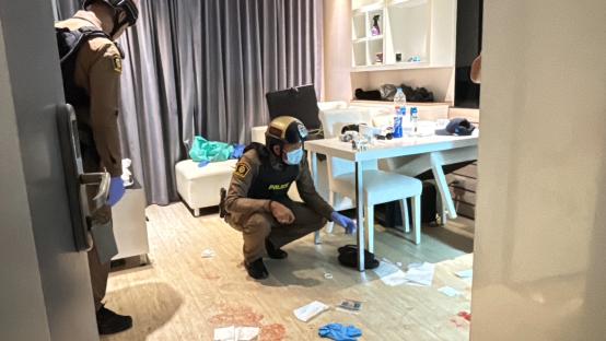 Police officers investigating a crime scene in a hotel room.