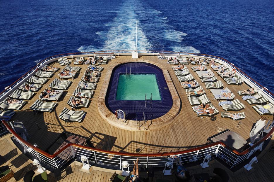Aerial view of a ship's deck with a pool and sunbathers.