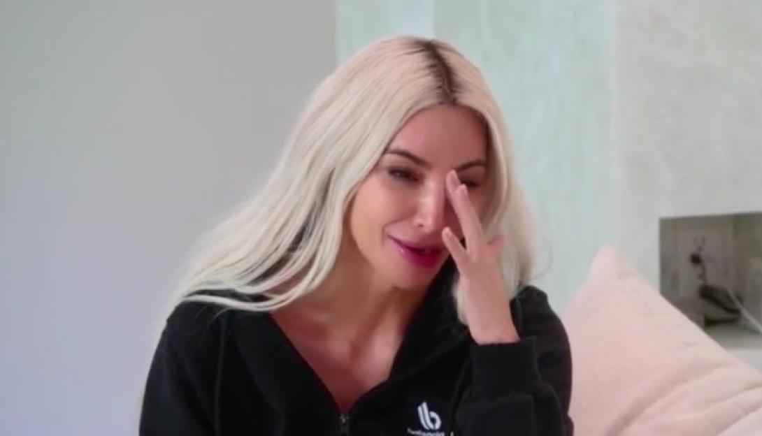 Kim Kardashian crying and wiping her eye.