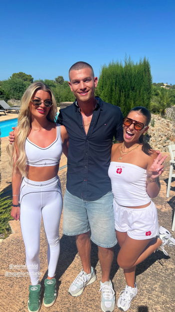 Three Love Island cast members posing together outdoors.