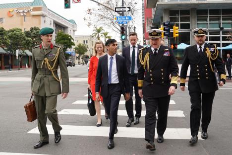 Prime Minister Rishi Sunak and military officials crossing a street.