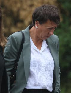 A woman in a green jacket and white shirt leaves court.