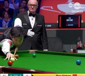 Snooker player Zhao Xintong taking a shot, with the referee watching.