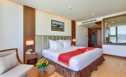 Hotel room with king-size bed and city view.