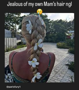 Woman's long blonde braid adorned with white flowers.