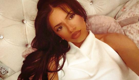 Woman with long dark hair wearing a white top.