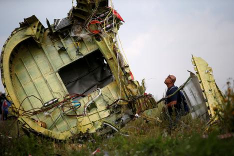 A crash investigator examines wreckage from the Malaysia Airlines Flight MH17 crash site.