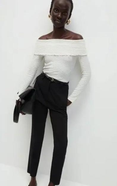 Model wearing a white off-the-shoulder top and black trousers.