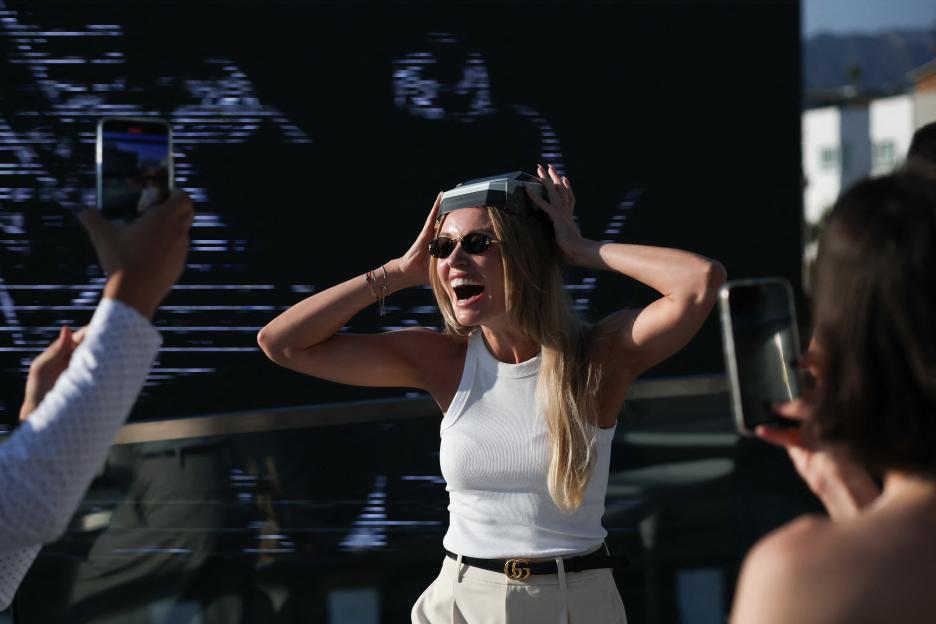 Woman wearing a Tesla Cybertruck food box as a hat.