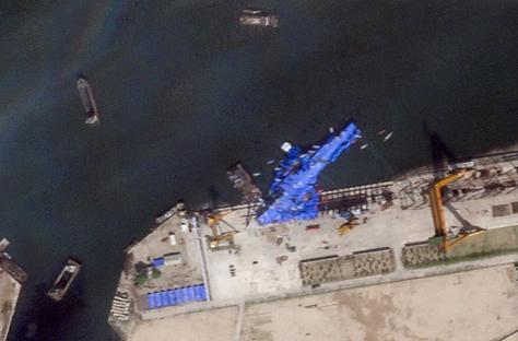 Satellite image of a North Korean warship covered in a blue tarp at a shipyard.