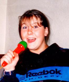 Young girl singing into a toy microphone.