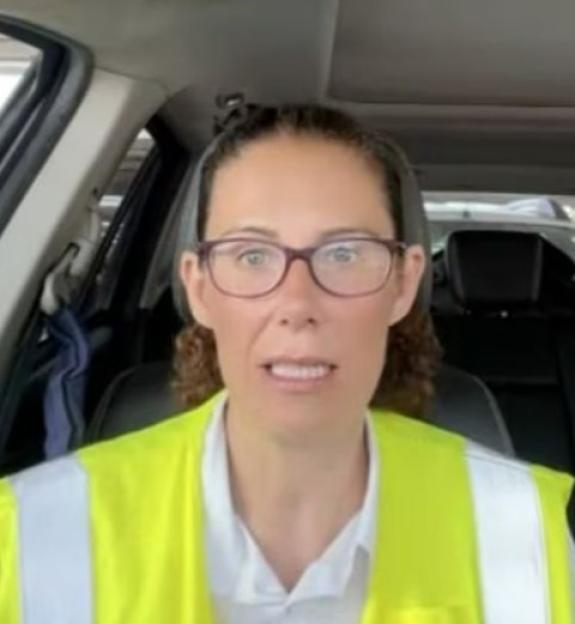 Woman in a car wearing a safety vest.