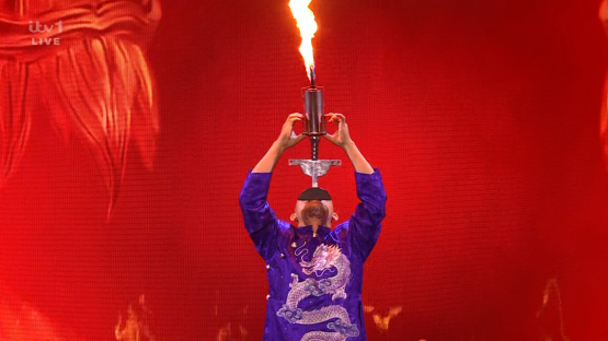 A performer balancing a flaming torch on his chin.