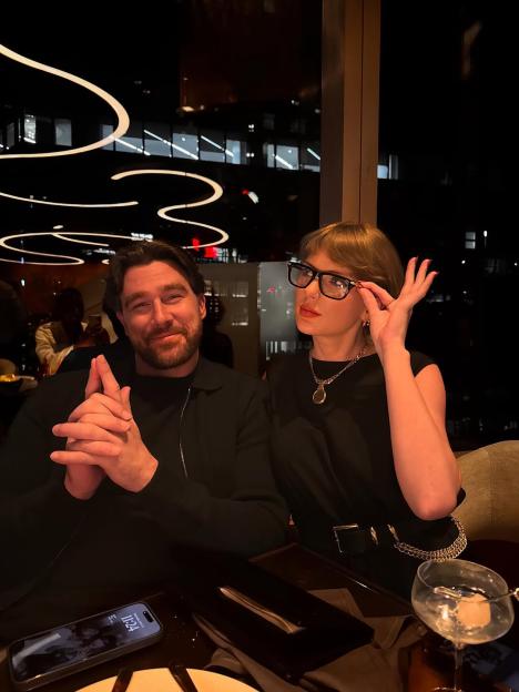 Taylor Swift and a man seated at a restaurant table.