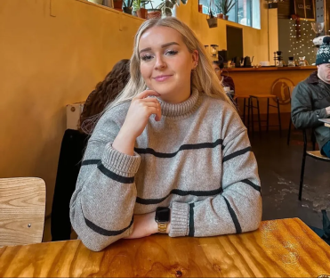 Woman in striped sweater sitting at a cafe table.