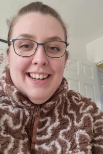 Woman wearing glasses and a brown and white fleece jacket.