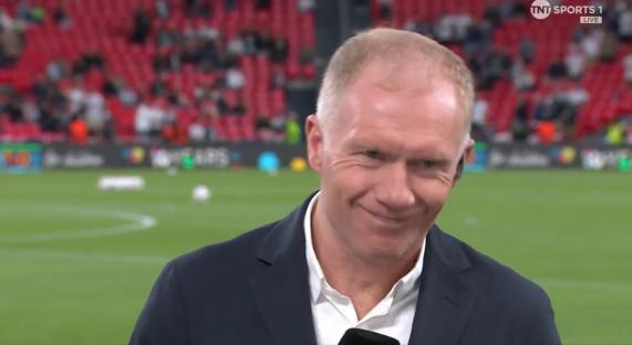 Smiling sports reporter in front of a blurred stadium background.