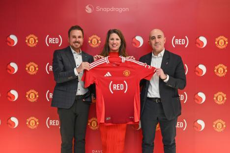 Three people holding up a (RED) Manchester United jersey.