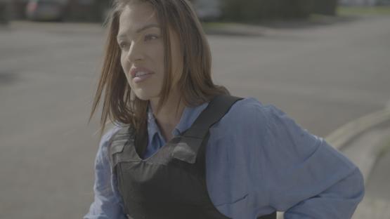 Woman in a bulletproof vest looking off to the side.