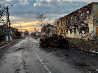 Destroyed vehicle on a street in a war-torn town.