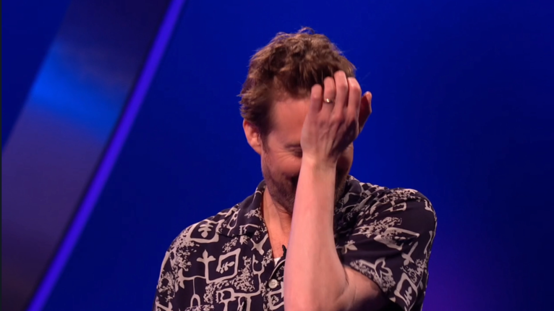 Man laughing and covering his face with his hand.