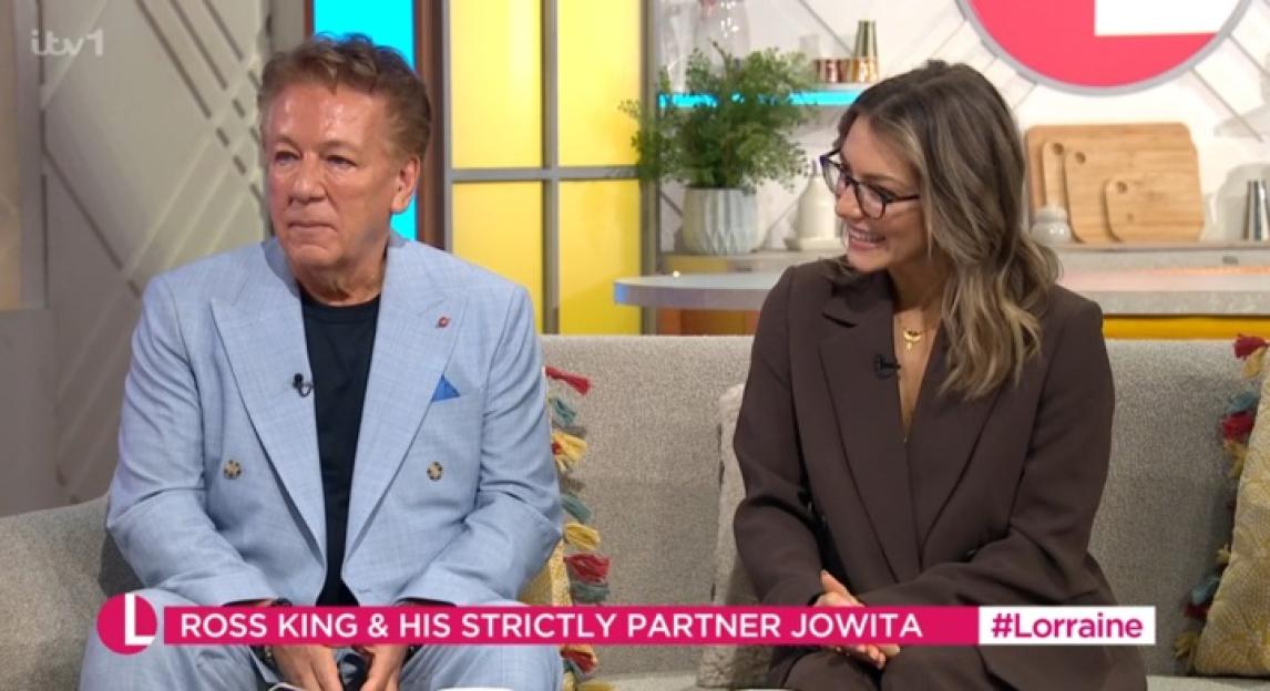 Ross King and Jowita Przystał sitting on a sofa during a television interview.