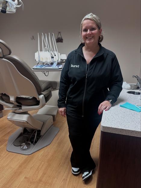 Woman in dental scrubs standing in a dentist's office.
