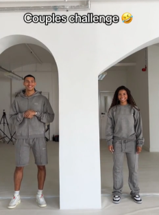 Couple in matching gray sweatsuits participating in a couples challenge.