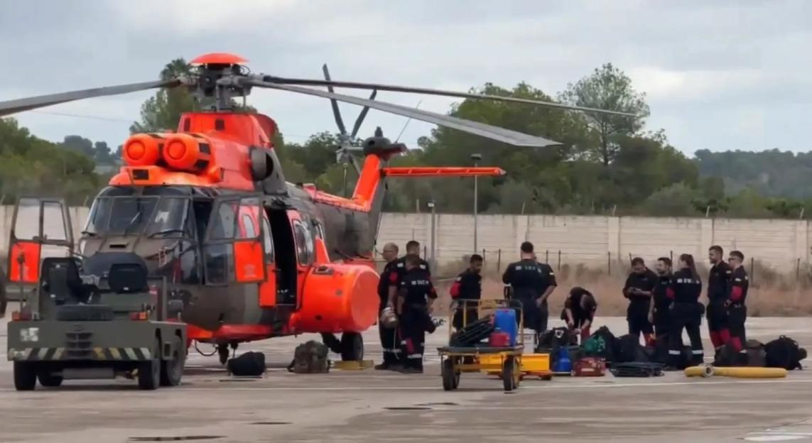 Military Emergency Unit members and a helicopter in Ibiza for flood relief efforts.